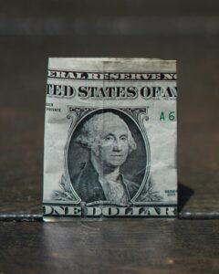 Billete de dólar cubierto por un paraguas, simbolizando protección ante el riesgo cambiario.